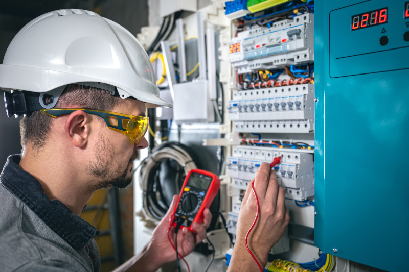 Technieker controleert een elektrische installatie met meetapparatuur in het kader van elektrische veiligheid en preventie op het werk.
